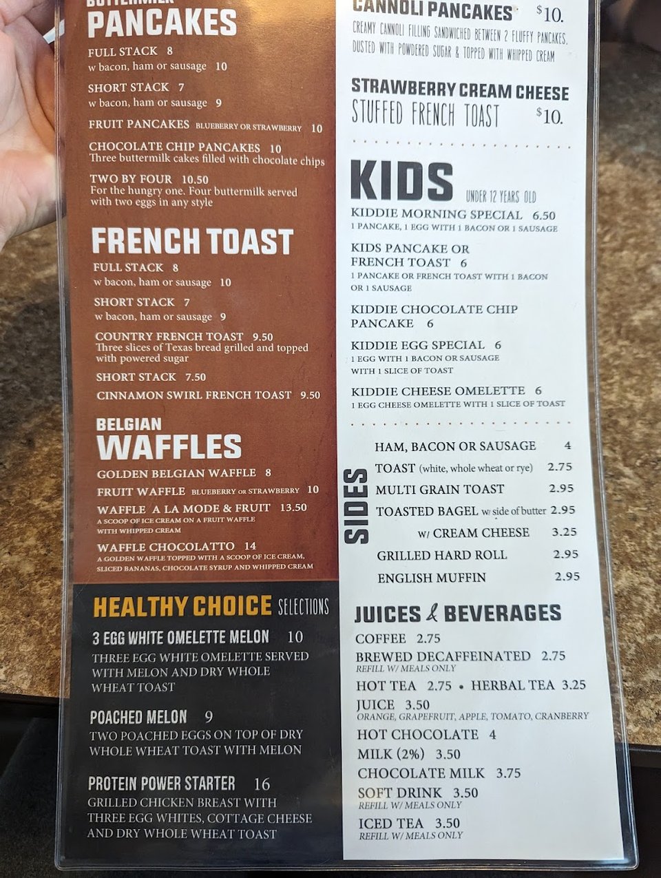 Hands holding a diner menu indoors.